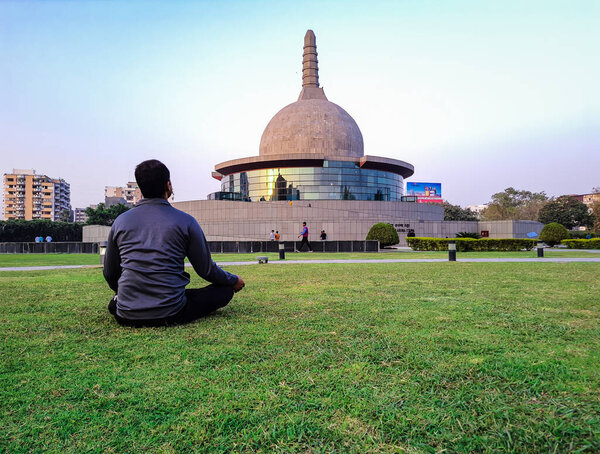 young man meditating at buddha stupa with bright blue sky at morning from different angle image is taken at buddha park patna bihar india on Apr 15 2022.