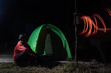 Geceleyin kamp macerası, ışık yolları ve tecrit edilmiş bir adam.