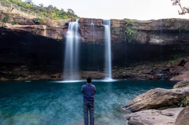 Şelale dereleri olan genç adam sabahleyin dağdan düşüyor uzun pozlu fotoğraf Krangsuri Şelalesi meghalaya Hindistan 'da çekiliyor..