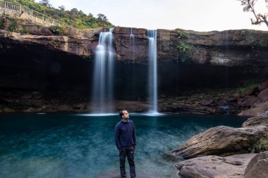 Şelale dereleri olan genç adam sabahleyin dağdan düşüyor uzun pozlu fotoğraf Krangsuri Şelalesi meghalaya Hindistan 'da çekiliyor..