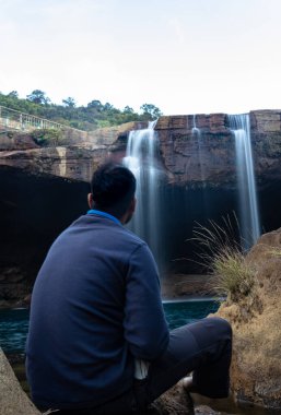 Şelale dereleri olan genç adam sabahleyin dağdan düşüyor uzun pozlu fotoğraf Krangsuri Şelalesi meghalaya Hindistan 'da çekiliyor..