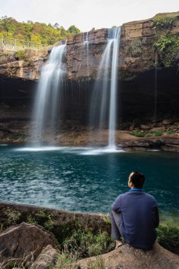 Şelale dereleri olan genç adam sabahleyin dağdan düşüyor uzun pozlu fotoğraf Krangsuri Şelalesi meghalaya Hindistan 'da çekiliyor..