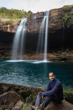 Şelale dereleri olan genç adam sabahleyin dağdan düşüyor uzun pozlu fotoğraf Krangsuri Şelalesi meghalaya Hindistan 'da çekiliyor..