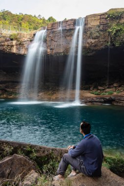 Şelale dereleri olan genç adam sabahleyin dağdan düşüyor uzun pozlu fotoğraf Krangsuri Şelalesi meghalaya Hindistan 'da çekiliyor..
