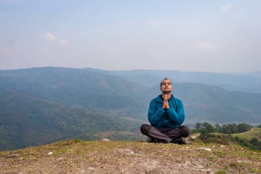 Tepenin zirvesinde sisli dağ öfkesiyle meditasyon yapan bir adam düz açılı görüntüden Hindistan 'da çekilmiştir..