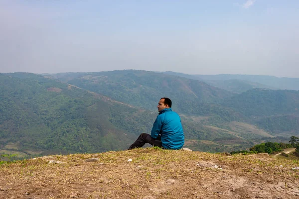 Tepenin tepesinde tek başına oturan adamın sisli dağ öfkesinin arka planı düz açıyla.