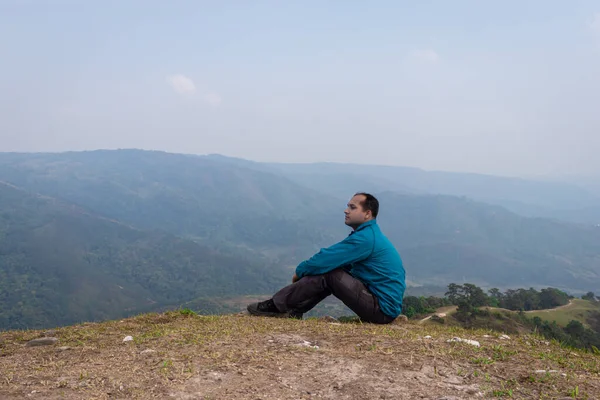 Tepenin tepesinde tek başına oturan adamın sisli dağ öfkesi ve düz açıdan çekilmiş görüntüsü Nongjrong meghalaya Hindistan 'da çekilmiştir..