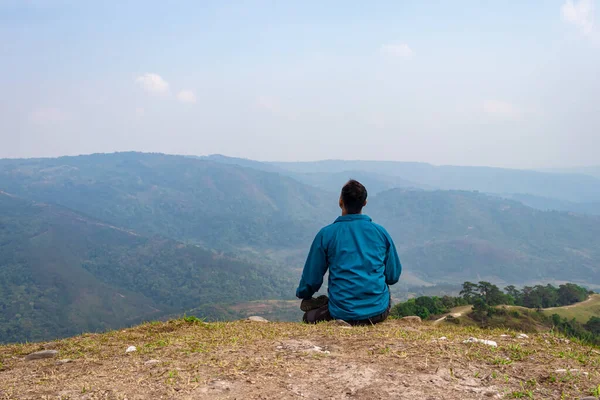Tepenin zirvesinde sisli dağ öfkesiyle meditasyon yapan bir adam düz açılı görüntüden Hindistan 'da çekilmiştir..