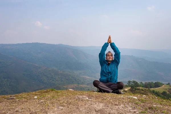 man meditating at hill top with misty mountain rage background from flat angle image is taken at nongjrong meghalaya india.