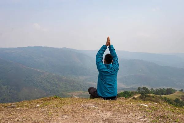 Tepenin zirvesinde sisli dağ öfkesiyle meditasyon yapan bir adam düz açılı görüntüden Hindistan 'da çekilmiştir..