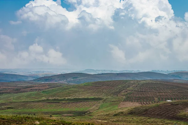 Düz açılı, parlak mavi gökyüzü ile dağlık tarım tarlaları