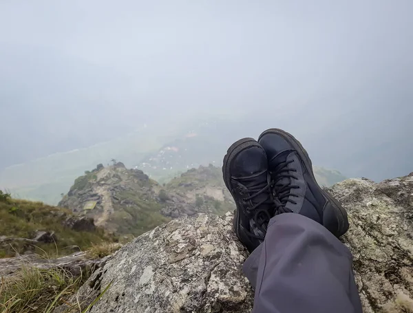朝の平らな角度から山の頂上で休んでいるハイカーの足 — ストック写真