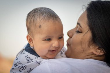 Sevimli bebek yüz ifadesi anne omuzunda düz açıyla dinleniyor.