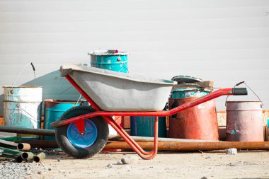 Duvara dayanan teneke ve kovaların arka planına karşı inşaat malzemeleri taşımak için bir tramvay.