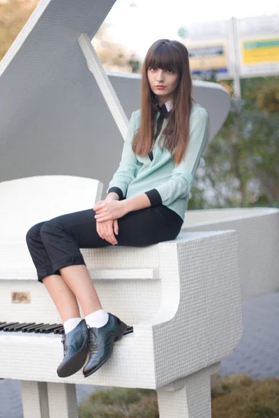 Beautiful girl sitting on the piano — Stock Photo, Image