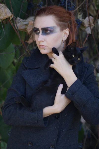 Рыжая девушка с черной кошкой — стоковое фото
