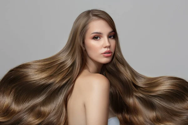 Lüks dalgalı saçlı genç bir kadının portresi. Saç ve makyaj.
