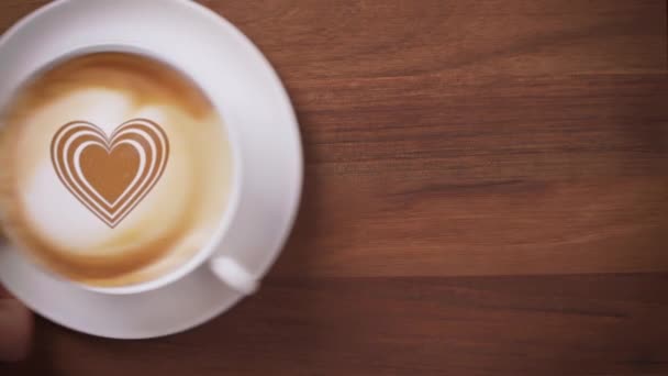 Vista superior de una mano que sirve café con el símbolo del corazón arte latte — Vídeos de Stock