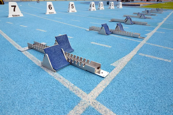 Atletismo começa blocos em uma pista de corrida azul em um estádio — Fotografia de Stock