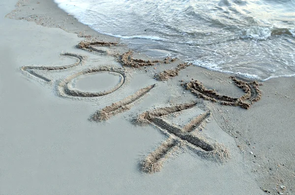 Neues Jahr 2014 kommt Konzept - Inschrift 2013 und 2014 auf einem Strand Sand, die Welle beginnt, die Ziffern 2013 zu bedecken — Stockfoto