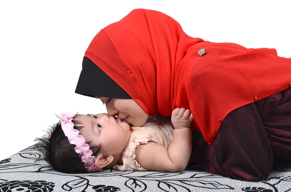 白い背景上に分離されて彼女のかわいい赤ちゃんの女の子にキス若いアジアのイスラム教徒の母親 ストック画像
