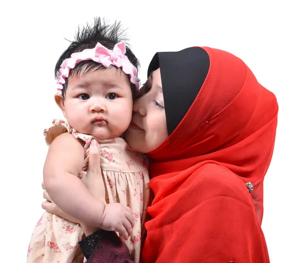 白い背景上に分離されて彼女のかわいい赤ちゃんの女の子にキス若いアジアのイスラム教徒の母親 ストック写真