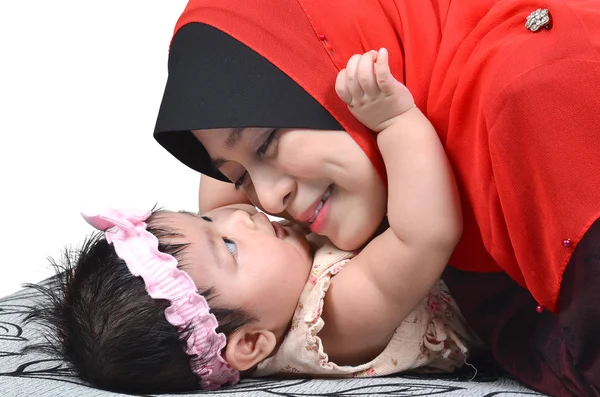 若いアジア イスラム教徒の母親を再生と白い背景で隔離された彼女のかわいい赤ちゃんの少女に笑みを浮かべて ストックフォト
