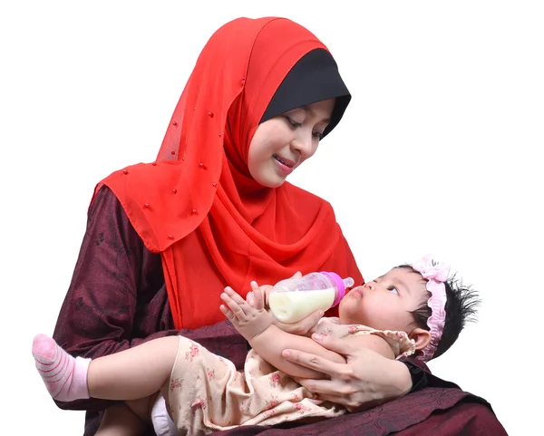 Young Asian muslim mother enjoying feeding her cute baby girl with a milk bottle isolated on white background — Stock Photo, Image