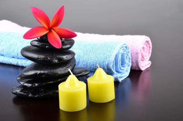 Beautiful frangipani flower with stones and towels with candles — Stock Photo, Image