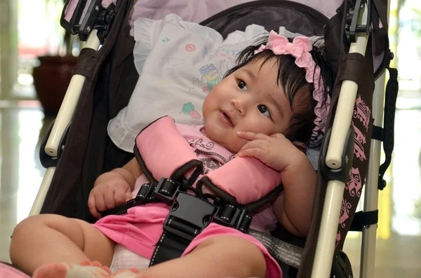 Söt asiatisk flicka leende medan du sitter i hennes barnvagn — Stockfoto
