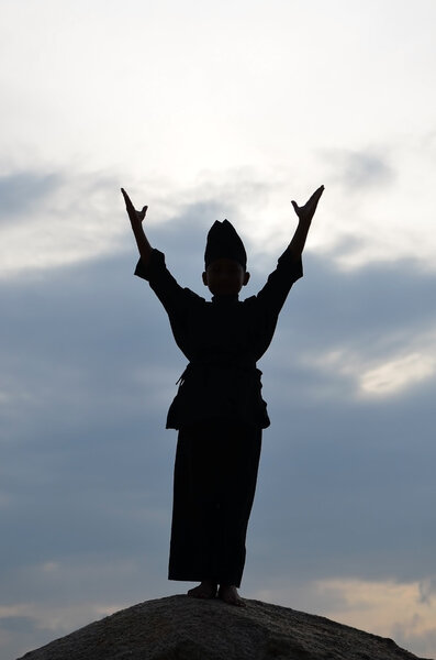 Silhouette of young boy performing a pencak silat, Malay traditional discipline martial art