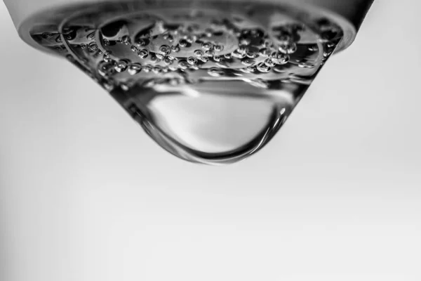 Big crystal clear water drop falling from the faucet. Black and white photography. — Stockfoto