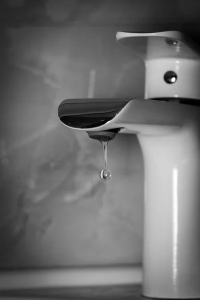 Klare Wassertropfen fallen aus dem Wasserhahn. Kontrast Schwarz-Weiß-Fotografie. — Stockfoto