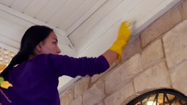 Mladá asijka v purpurovém svetru s rukavicemi otírá strop — Stock video
