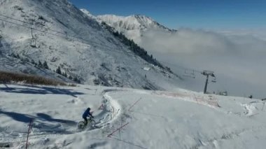 Kışın bisikletle MTB bisiklet sürmek. Kar dağlarında bisiklet süren bir motorcu.