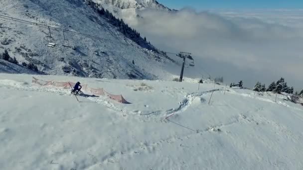 Motociclista em montanhas nubladas de inverno andar de bicicleta na neve. Vista aérea — Vídeo de Stock