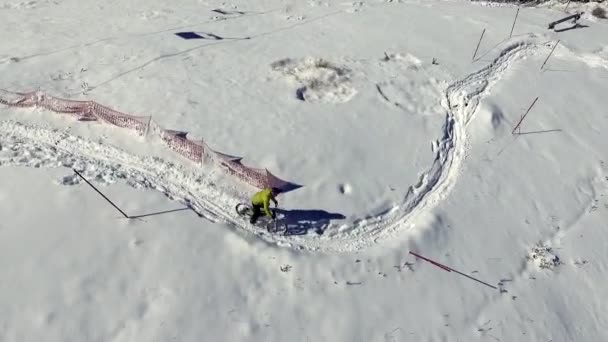 Cyclist rides a mountain bike on a snowy path. Aerial View from above drone shot — Stock Video