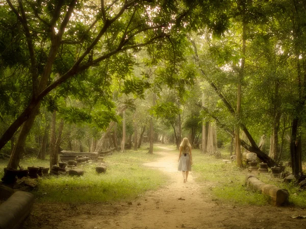 Mujer joven caminando por el misterioso camino hacia el bosque encantado —  Fotos de Stock