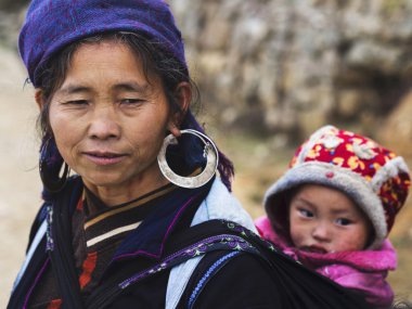 çocuk taşıyan ve geleneksel kıyafetleri, sapa takmış bir hmong kadın,