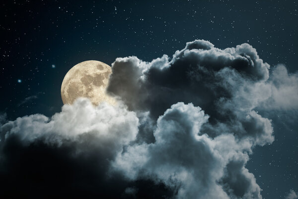Full moon behind the clouds on a starry night