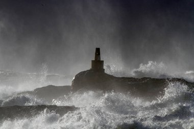 Storm on the coast seeing rocks and cliffs covered with spray after splash of a big breaking wave.