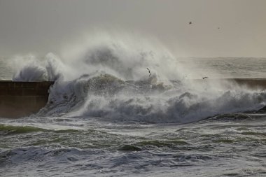 Big breaking waves over river mouth pier, north of Portugal.