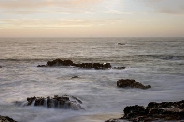 Alacakaranlıkta dalgalar çekildiğinde Rocky sahili. Uzun pozlama. Kuzey Portekiz kayalık kıyıları.