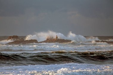 Fırtınalı dalgalar günbatımında sıçrıyor. Kuzey Portekiz maliyeti.