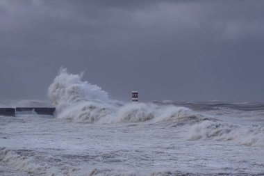 Fırtınalı dalga, Douro nehrinin ağzında kara bulutlu gökyüzüne sıçrıyor, Porto, Portekiz