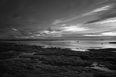 Alacakaranlıkta kızılötesi kayalık plajı. Uzun soluklu. Siyah ve beyaz.