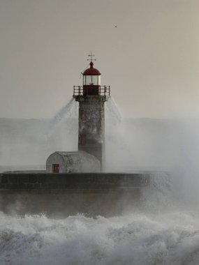 Douro Nehri 'nin ağzındaki eski deniz feneri fırtınada şiddetli dalgaların çarpmasından sonra akan suyu görüyor.