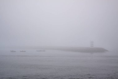 Douro nehri ağzı güney rıhtımında ve sislerin arasında küçük balıkçı tekneleri görüyor. 