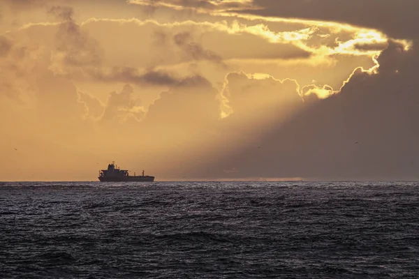 在冬季日落时 商船在地平线上出现 尼罗巴岛石质海岸 — 图库照片