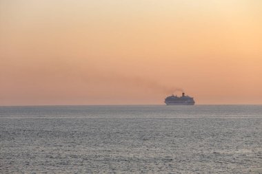 Yolcu gemisi sakin turuncu bir günbatımında kuzey Portekiz kıyısından geçiyor.